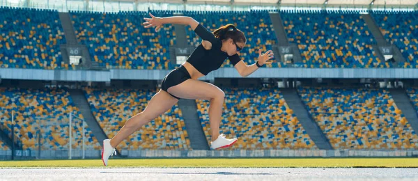 Sett fra siden av en kvinnelig idrettsutøver som sprinter på en løpebane – stockfoto