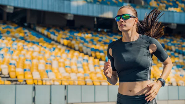 Close up shot of female athlete sprinting on a running track in a stadium — Stock Photo, Image