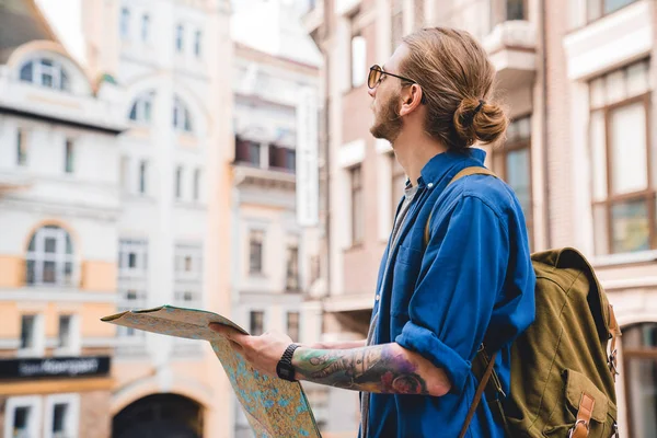 Moderner Tourist. schöner junger Mann in lässiger Kleidung, der Landkarte in der Hand hält und im Freien wegschaut — Stockfoto