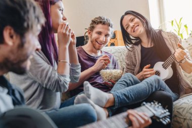 Neşeli arkadaşlar müzik enstrümanları çalıyor ve evde eğleniyorlar.