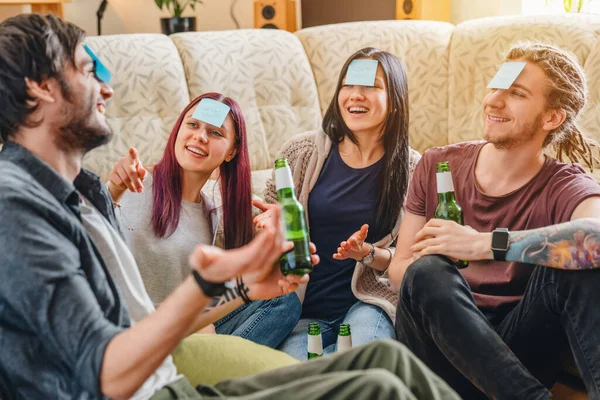 Cheerful friends with sticky notes on foreheads playing name game with beer