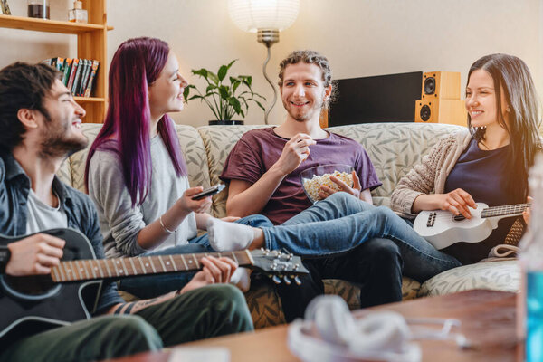 Счастливые друзья, играющие на музыкальных инструментах, развлекаясь в домашней гостиной
