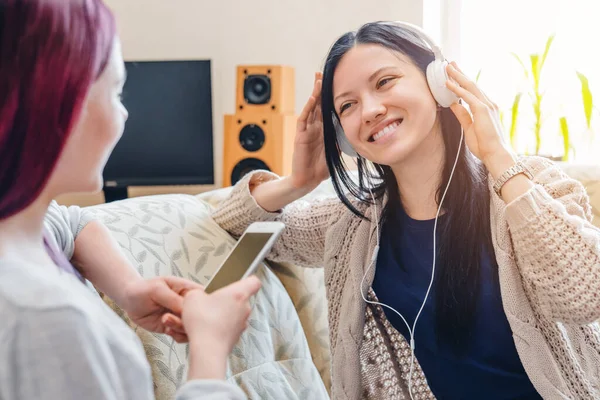Dua Wanita Mendengarkan Musik Smartphone Dengan Earphone Duduk Sofa Rumah — Stok Foto