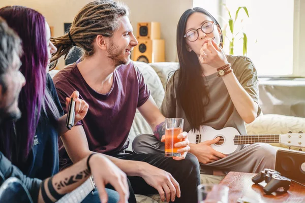 Evde arkadaşlarıyla müzik enstrümanları çalarken esrar içen genç bir kadın.