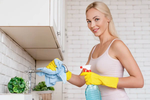 Uśmiechnięta Kobieta Rękawiczkach Ochronnych Myjąca Kran Szmatą Kuchni Domowej Patrząca — Zdjęcie stockowe