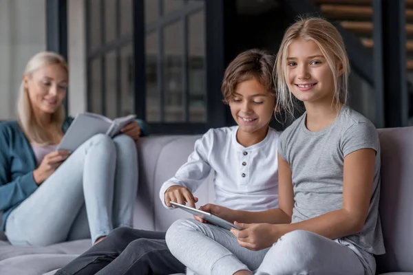 Crianças Usando Tablet Digital Enquanto Mãe Livro Sofá — Fotografia de Stock