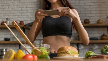 Genç kız blogcu yemek fotoğraflıyor ve sağlıklı beslenme ve sebzeleri teşvik ediyor.