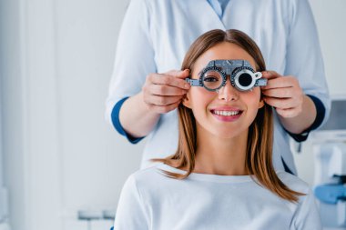 Female patient checking vision in ophthalmological clinic clipart