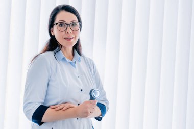 Dermatoskoplu doktor portresi kameraya bakarken gülümsüyor.