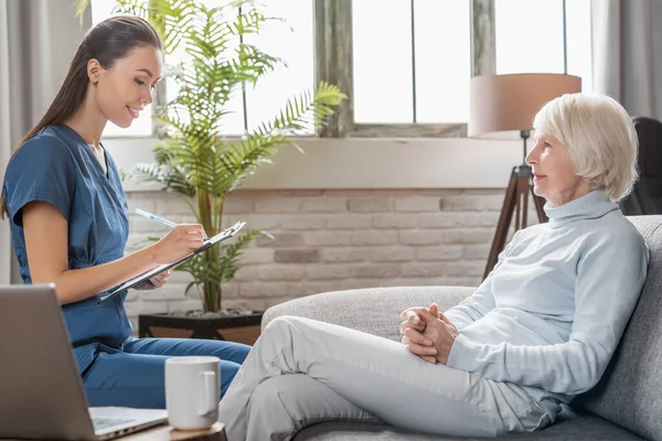 Female Caregiver Writing Tablet Information Senior Woman Indoors — Stock Photo, Image