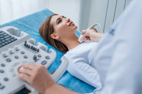Modern klinikte ultrason tarayıcısıyla boynunu muayene ettiren kadın.