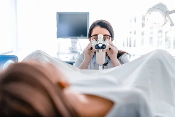 Yetişkin kadın jinekolog hastanedeki hastayı colposcope kullanarak muayene ediyor.