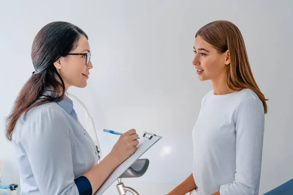 Klinikte hasta ile çalışan yetişkin bir kadın jinekolog.