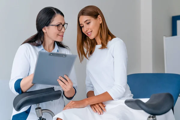Modern klinikte hastalarla çalışan gülümseyen kadın jinekolog.