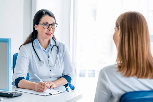 Modern klinikte çalışan ve hastaları dinleyen yetişkin bir doktor.