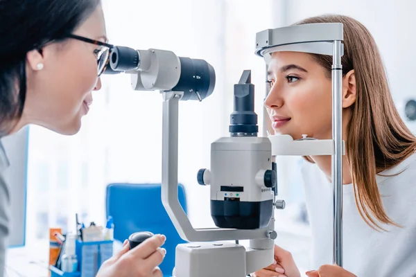 眼科クリニックでの女性医師と患者のサイドビューショット ロイヤリティフリーのストック写真