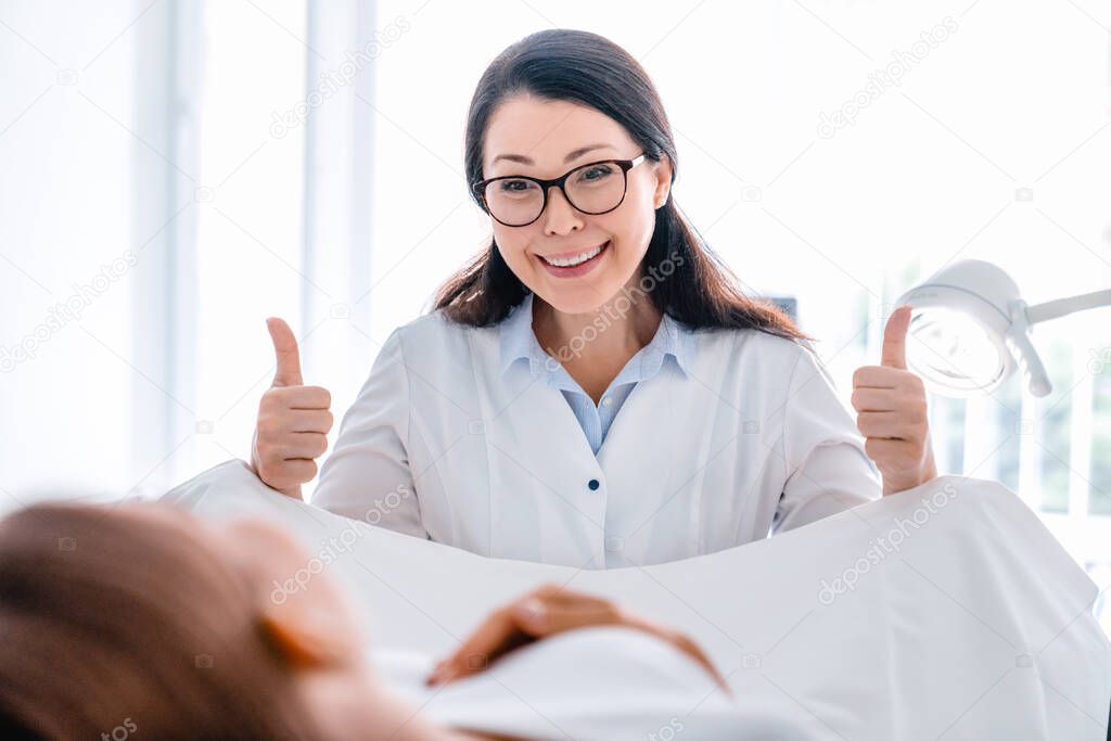 Smiling mid adult gynecologist examines a woman in modern clinic
