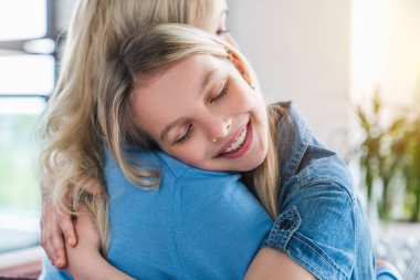 Mutlu anne-kız kucaklaşması. Evin içinde gözleri kapalı.