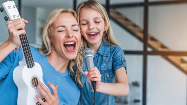 Kafkasyalı anne ve küçük kız evde karaoke yapıyorlar.