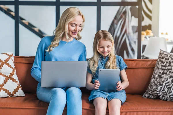 Hermosa Joven Madre Hija Usando Gadgets Sonriendo Mientras Sienta Sofá — Foto de Stock