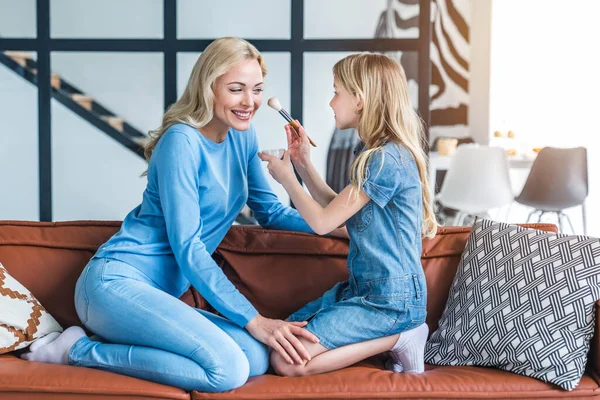 Madre Con Hija Pequeña Divirtiéndose Haciendo Cosméticos Maquillaje Sofá Casa —  Fotos de Stock