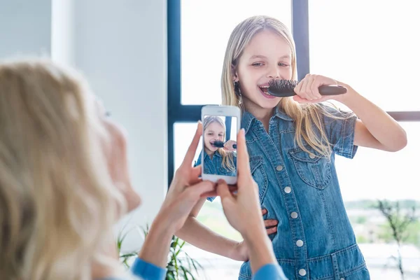 Güzel Bir Kadının Akıllı Telefonuyla Kızının Şarkı Söyleyip Evde Eğlenirken — Stok fotoğraf