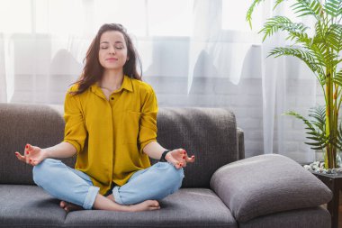 Huzurlu bir milenyum kızı derin derin meditasyon yaparken yoga egzersizleri yapıyor ve meditasyon yapıyor.