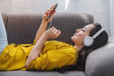 İnternette kulaklıkla müzik dinleyen genç bir kadının yan görüntüsü.