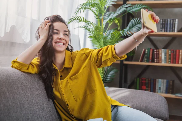 Šťastná Mladá Žena Přičemž Selfie Zatímco Sedí Gauči Obývacím Pokoji — Stock fotografie