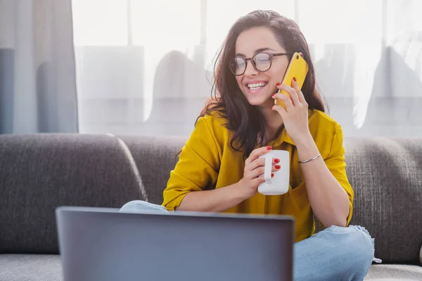 Fröhliches Mädchen Telefoniert Und Trinkt Morgenkaffee Während Sie Mit Laptop — Stockfoto