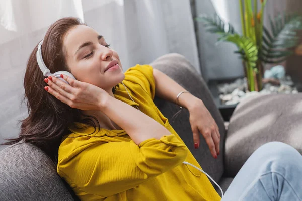 Wanita Yang Mendengarkan Musik Menggunakan Headphone Sambil Duduk Sofa Ruang — Stok Foto