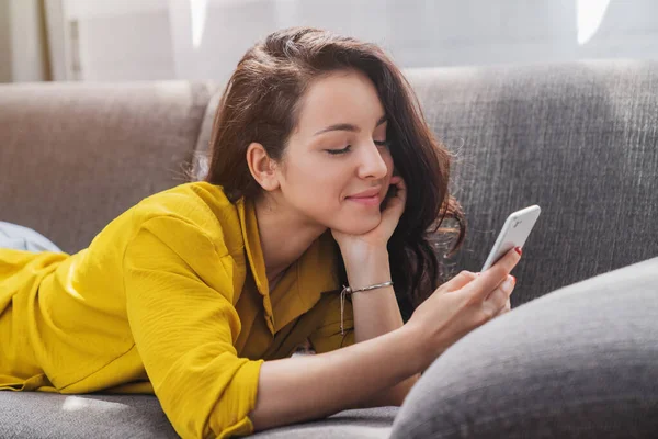 Relajada Mujer Sonriente Sofá Con Teléfono Inteligente Mensajes Texto Casa —  Fotos de Stock