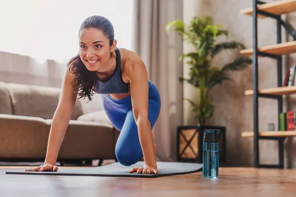 身穿蓝色运动服的漂亮女性在家里客厅做健身锻炼 — 图库照片