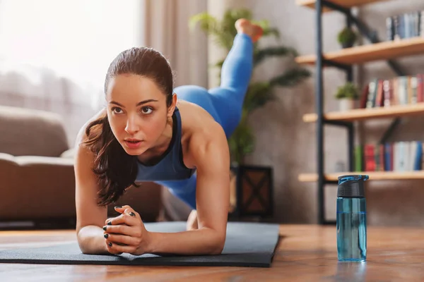 Spor giyimli, formalı genç bir kadın paspasın üzerinde çalışıyor.