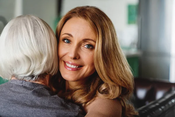 Head shot of happy young woman hugging old senior mother