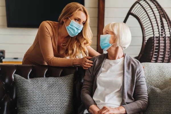 Senior Kvinde Medicinsk Maske Med Socialrådgiver Besøger Hende Derhjemme - Stock-foto