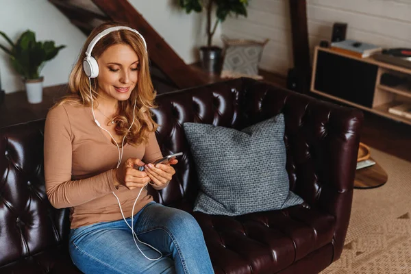 Wanita Paruh Baya Yang Menarik Duduk Sofa Dan Mendengarkan Musik — Stok Foto