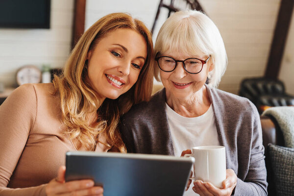 Cheerful Senior Woman Cup Tea Her Daughter Using Tablet Home Royalty Free Stock Photos