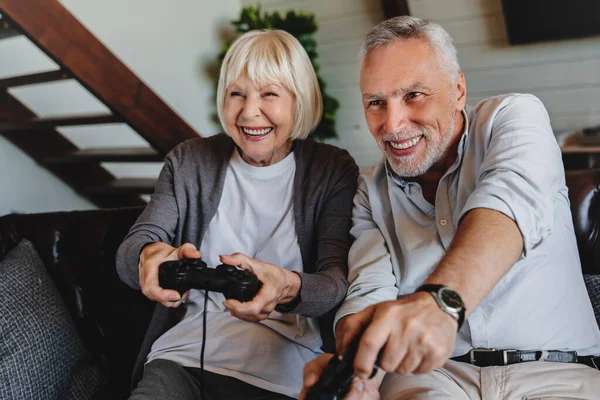 Para Senior Yang Ceria Duduk Sofa Dan Bermain Video Game — Stok Foto