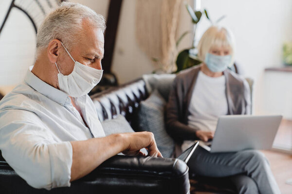 Mature Couple Sitting Face Masks Bright Waiting Room Home Laptop Stock Photo