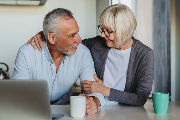 Senior Couple Hugging Using Laptop Kitchen Home Stock Image