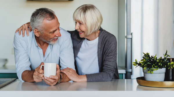 Mature Woman Hugging Her Husband Home Kitchen While Drinking Coffee Stock Picture