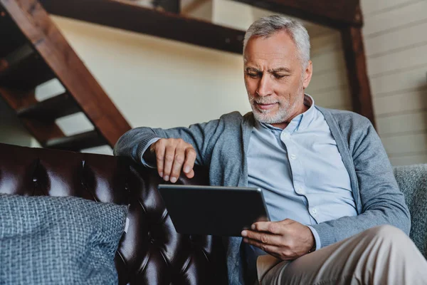 Reifer Kaukasier Surft Hause Auf Digitalem Tablet Stockfoto