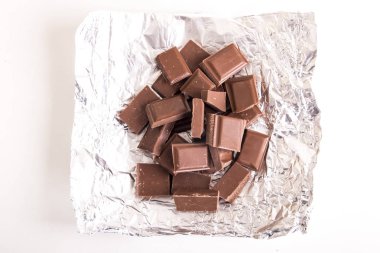 Gümüş parlak folyo üzerinde kırık kahverengi çikolata parçaları 