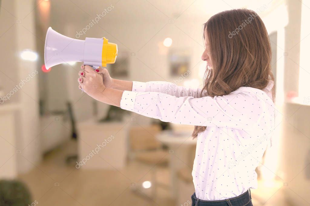 Young woman shouting with megaphone over blurred background