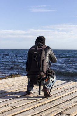 arkadan görünüşü fotoğrafçı adam şapkalı fotoğraf makinesi fotoğraf denizde su çekme 