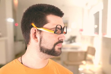 Beyaz adam baş aşağı gözlüklü ve uzağa bakarak turuncu tshirt