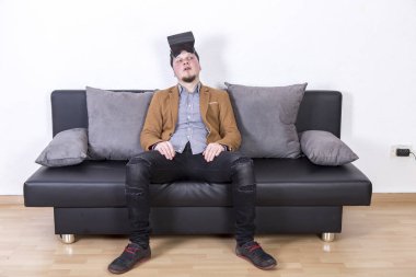 VR gözlük takan ve odasında kanepede oturan adam 