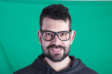 poz ve kameraya bakarak yeşil bir arka plana dayanır mutlu bir adam portresi