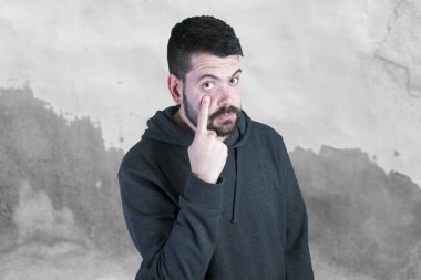 adam gri kapşonlu parmak ile göz açma